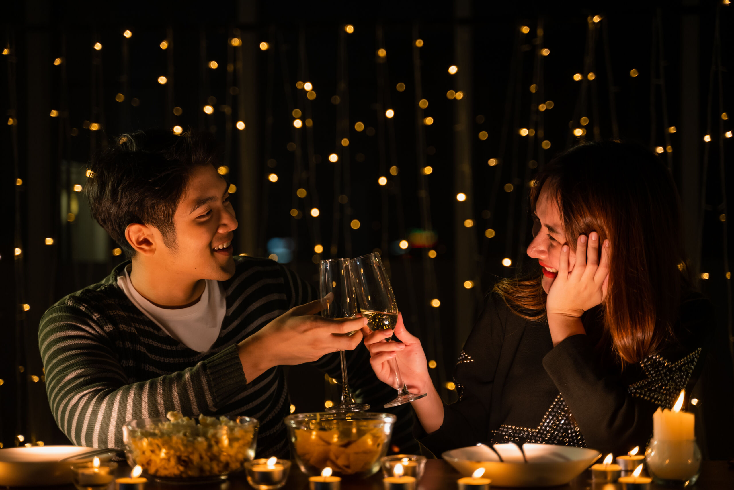 Couple toasting with wine in romantic candlelit setting.