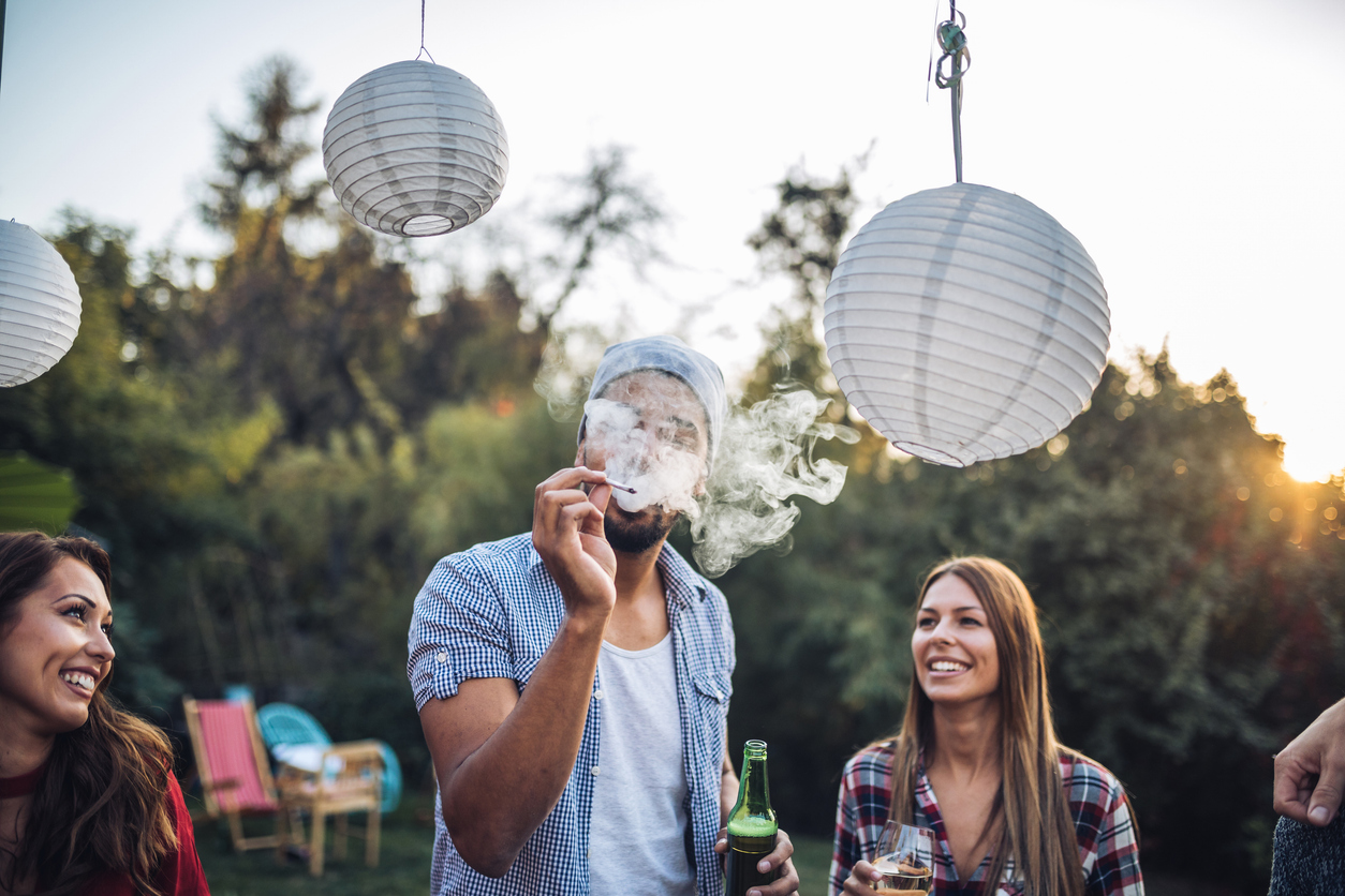 Exploring the outdoors with cannabis - A man smoking marijuana while having a party with his friends.