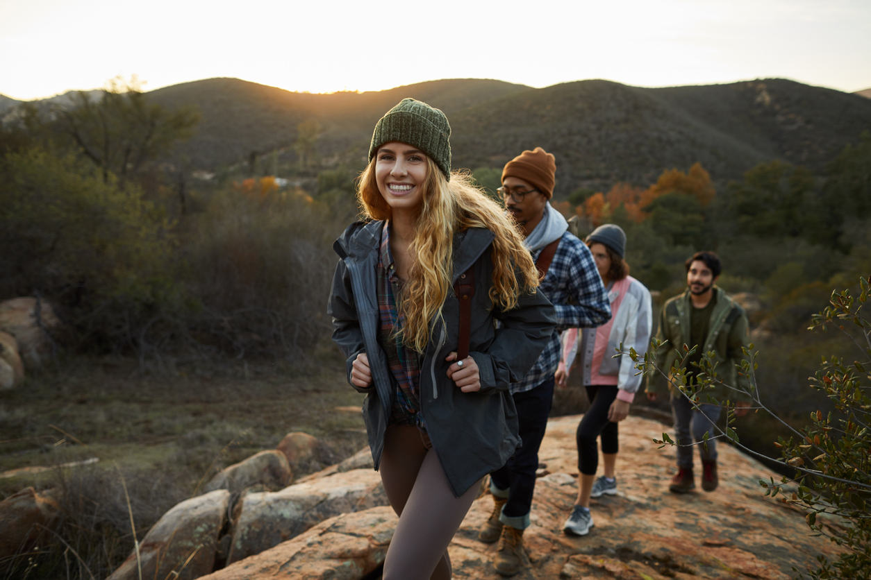 Smiling young woman and friends hiking up a hill together