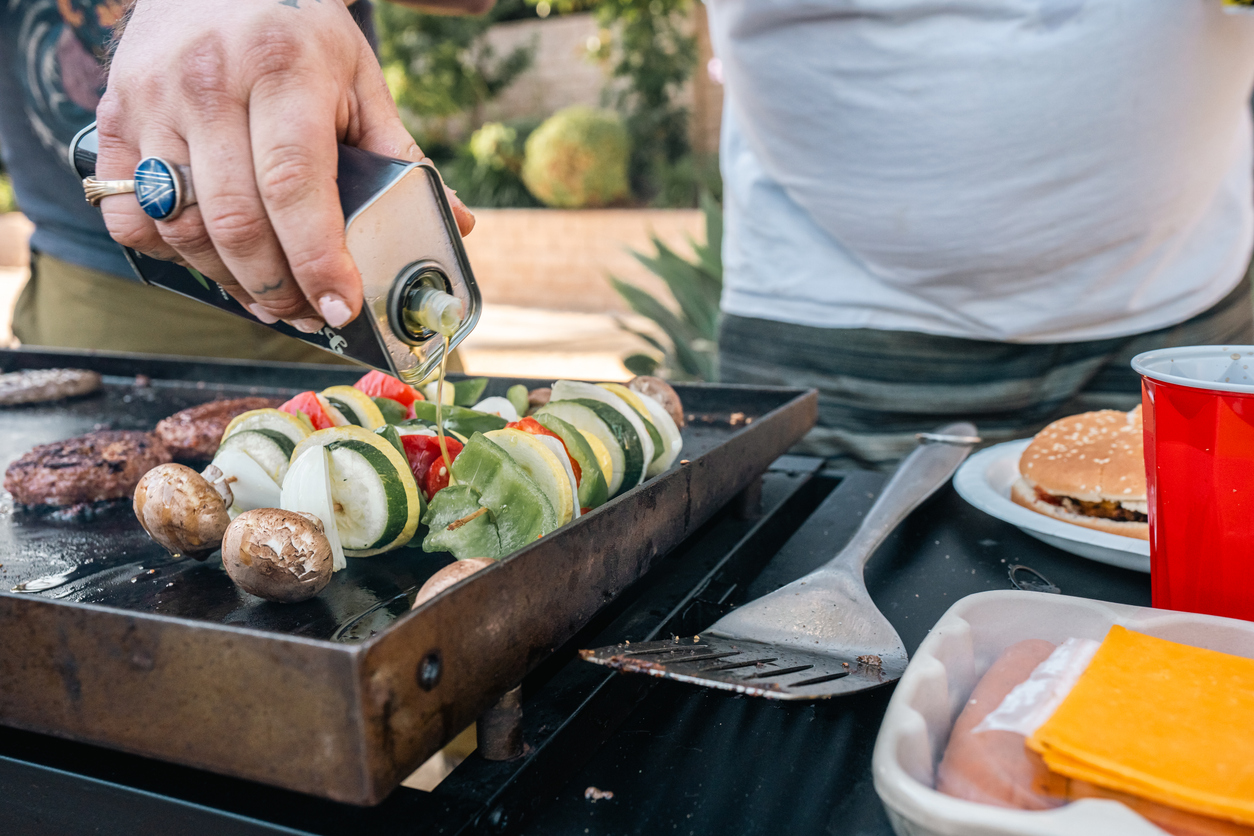 A man puts cannabis-infused BBQ olive oil on vegetable skewers to add flavor.