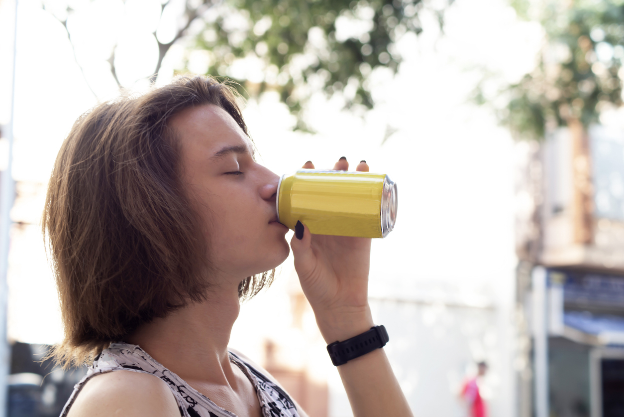 On a hot summer day, a teenage girl is sipping a cannabis-infused CBD drink from a can.