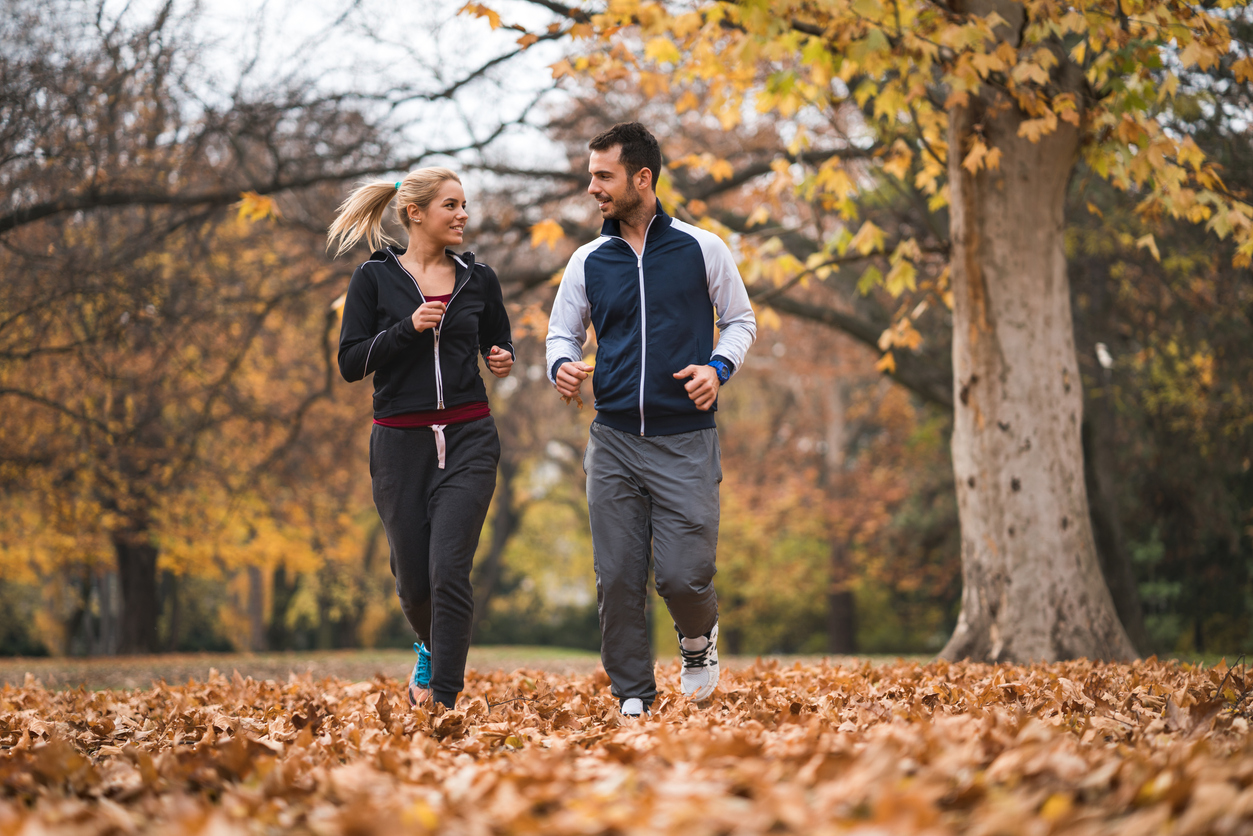 A young happy couple is jogging in the park in the Fall.