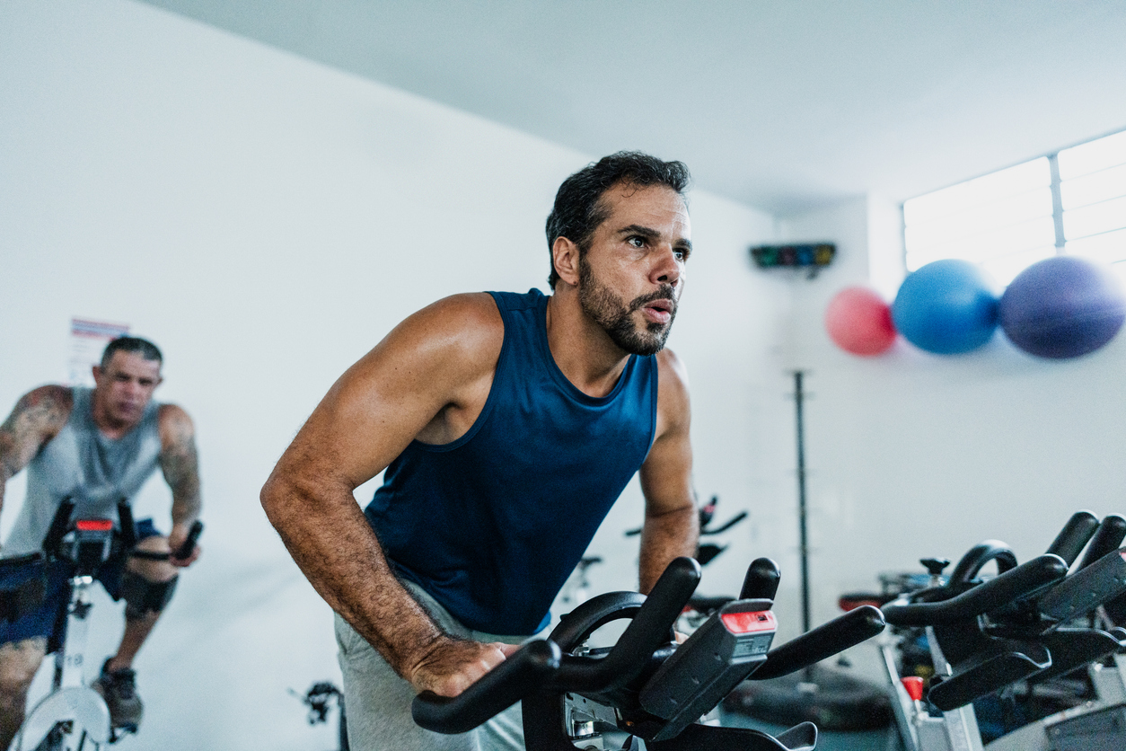 A man exercising using a bicycle workout machine in the gym.