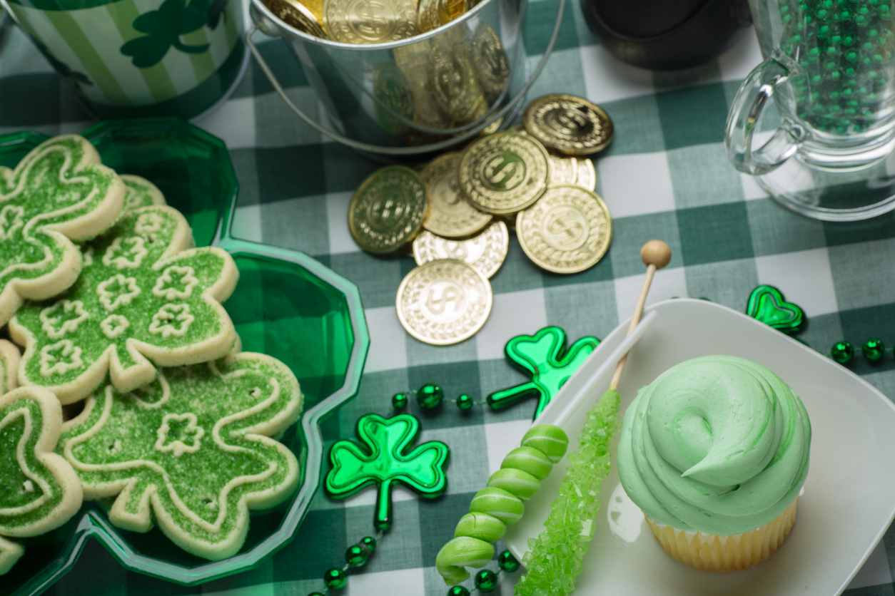 Using CBD oil for your treats - St. Patrick’s Day cookies, cupcakes, and decorations placed on a table.