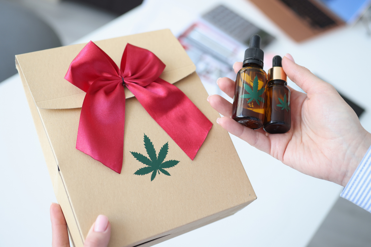Buying cannabis gifts - A woman holding a package of cannabis products and two bottles of cannabis tinctures.